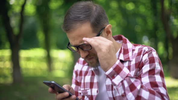 Poor Eyesight Man in Eyeglasses Reading Smartphone Message, Ophthalmology