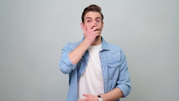 Confused young man in denim jacket over light grey background put palm on face facepalm gesture