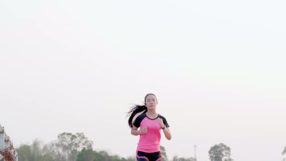 Young sport Asian woman running exercise for good health in pink sportswear on outdoor