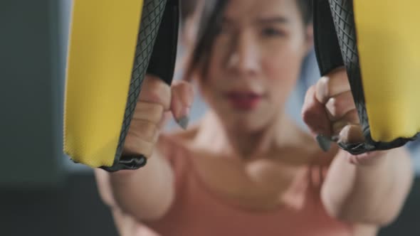 Asian young sportswoman exercising workout on TRX exercise rope at fitness stadium or gym club.