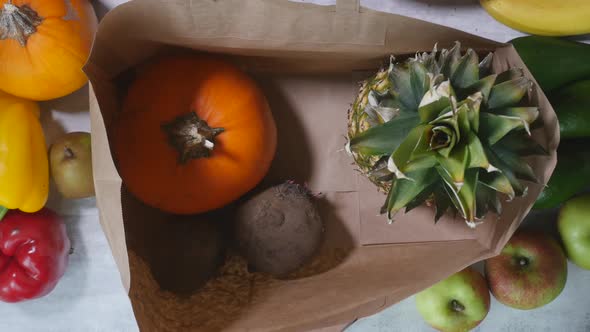 Woman Hand Put Fruits and Vegetables Into Cardboard Bag