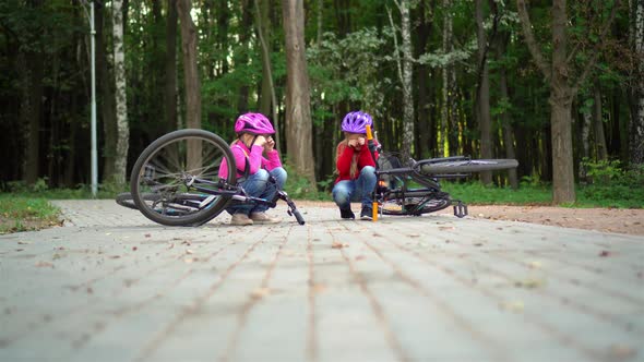 Two little girls in protective helmets collided on bicycles and cry.