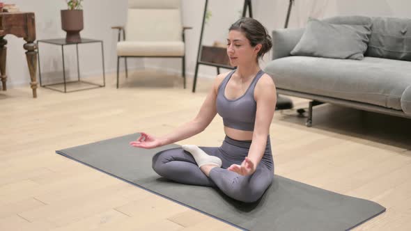 Peaceful Young Indian Woman Meditating on Yoga Mat at Home