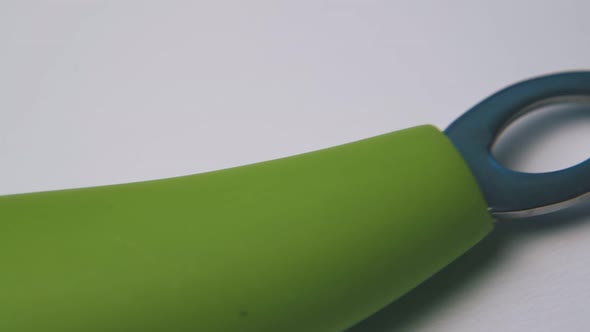 Vegetable Peeler with Green Handle Lies on White Surface