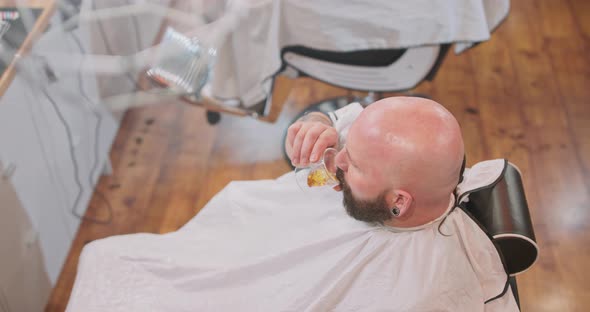 Top View of Young Bearded Man's Head with Clean Shaven Head is Sitting on the Barber's Chair with