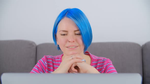 Cute white girl with blue hair learning online with laptop computer and internet connection in 4k