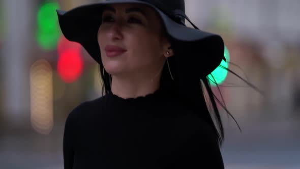 Close-up Portrait of a Fashionable Woman with Black Hair, Black Hat and Purple Coat Walking