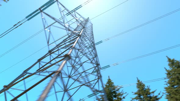 High voltage electricity pylons in a mountain forest. Blue sky in background. 4k