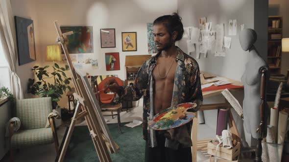 Portrait of Indian Artist with Palette in front of Canvas in Studio