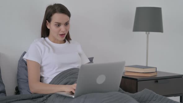 Woman Celebrating Success on Laptop in Bed