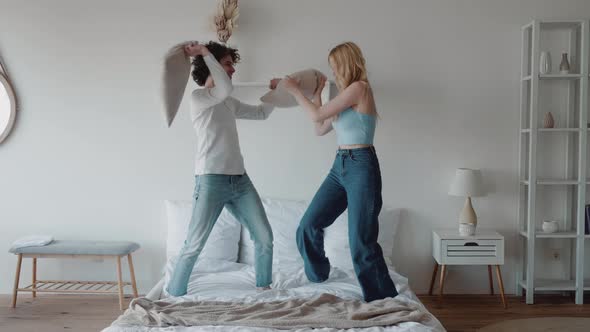Beautiful Couple Having Pillow Fight on Bed in the Morning