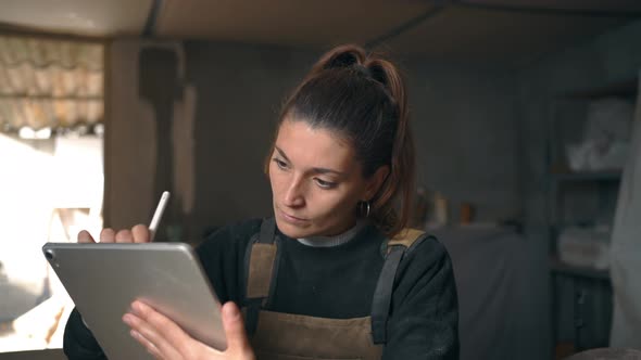 Craftswoman drawing on graphic tablet in workshop