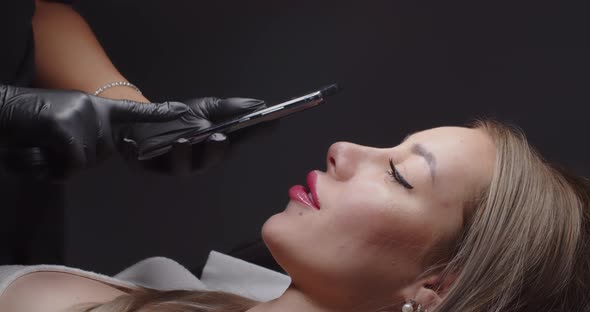 The Girl on a Mobile Phone Takes Pictures of the Client's Face in a Beauty Salon