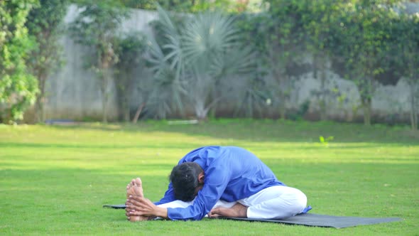 Indian man doing Janusirsasana or Head to Knee Yoga pose in an Indian traditional outfit