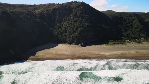 Steep mountain ranges and hiking trails along black sand beach on New Zealand's West coast