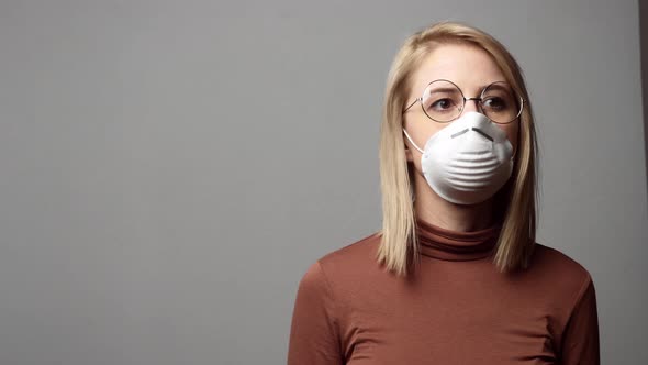 Blonde woman in protective mask on grey background
