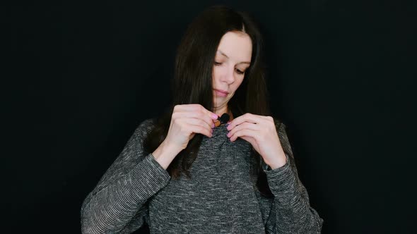 Woman Brunette Attaches the Lavalier Microphone To the Blouse on a Black Background.