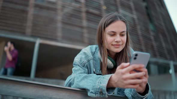 Meditative blonde woman wearing jeans jacket typing by phone