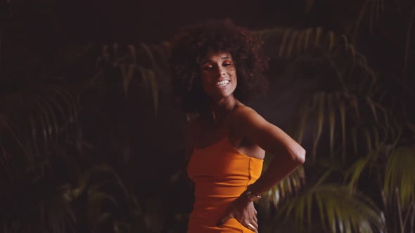 Model With Afro Smiling Then Posing With Attitude To Camera In Orange Dress