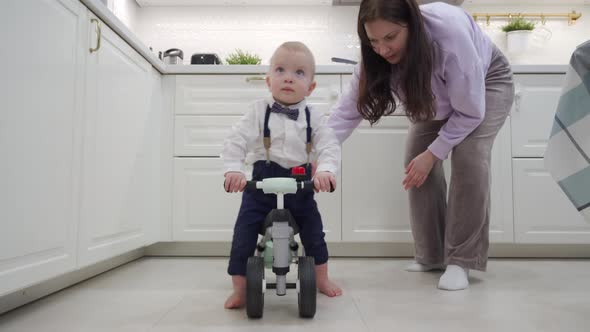 Mother and Baby Boy Play on the Floor Mother Teaches 1 Year Old Child to Ride a Balance Bike