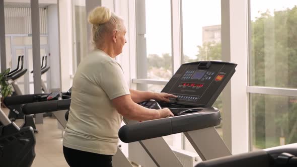 Eldest Woman of Retirement Age Runs on a Treadmill in the Gym