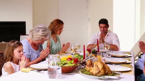 Extended family saying grace before christmas dinner