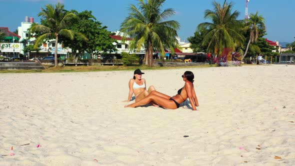 Young smiling girls on holiday in the sun on beach on summer white sandy and blue background 4K