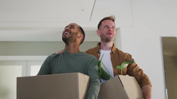 Multi ethnic gay male couple carrying packing boxes into house