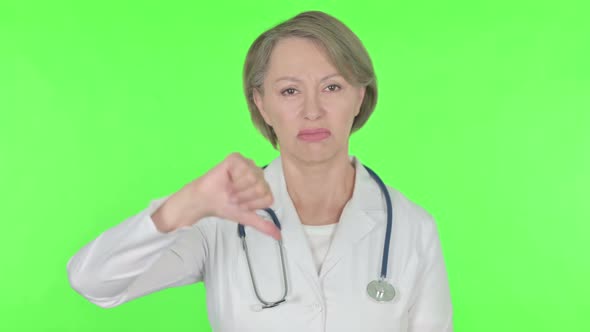 Thumbs Down By Old Female Doctor on Green Background