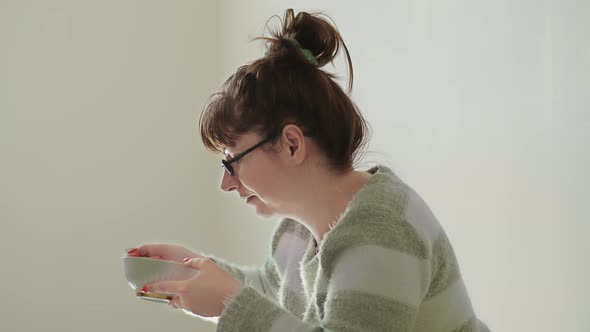 Brunette Woman Sitting on the Floor and Eating Noodles on Stools Economic Crisis Cheap Food