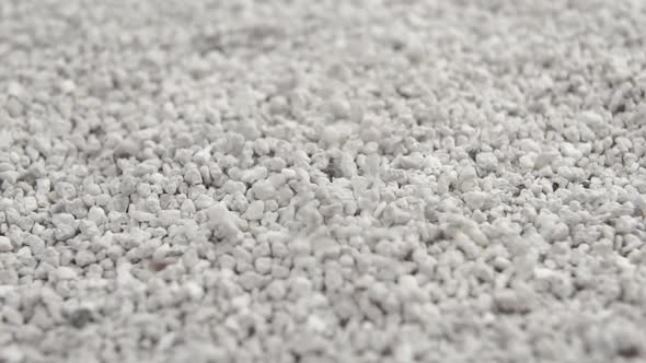 Clumping bentonite cat litter. Grey fine-grained toilet particles falling in slow motion