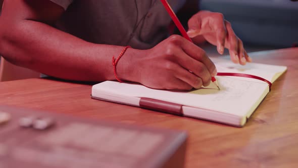 Hands of Songwriter Writing Lyrics in Notepad in Home Recording Studio