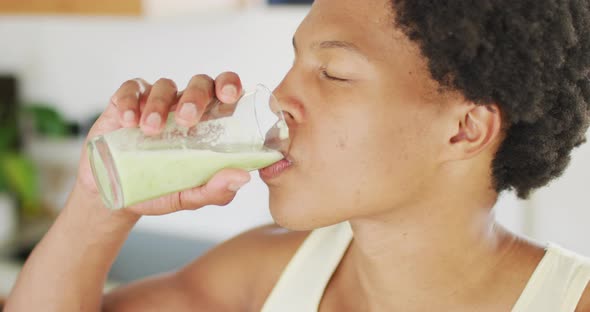 Fit african american man cooking, drinking healthy green smoothie
