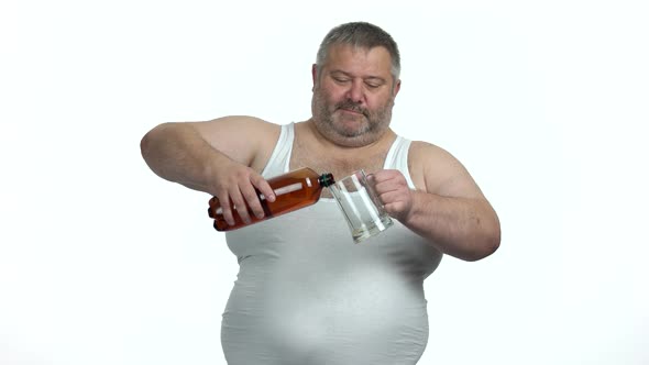 Fat Man Pours Beer From Bottle Into a Beer Glass