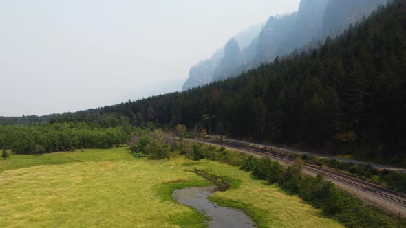 Low angle drone shot of the sheer cliffs of the canyon and a clearing with a creek in the Columbia R