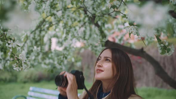 Young woman smiling and appreciating the beauty of blossoming trees while taking pictures