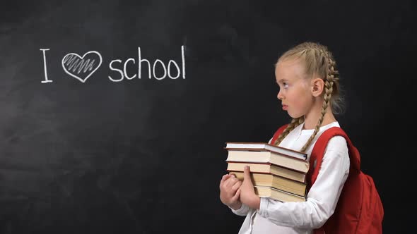 Naughty Schoolgirl With Books Standing Near Blackboard, I Love School Written