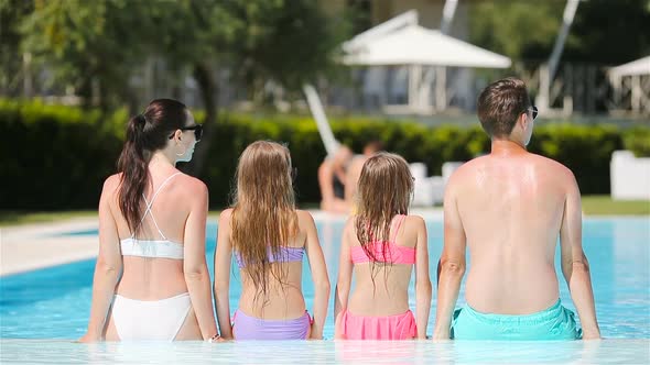 Happy Family of Four in Outdoors Swimming Pool