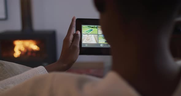 Back view of african american woman using smartphone and lying on sofa