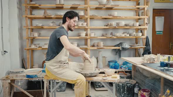Male Potter Making Ceramic Item on Potter's Wheel Watering Clay and Forming Tracking Shot Slow