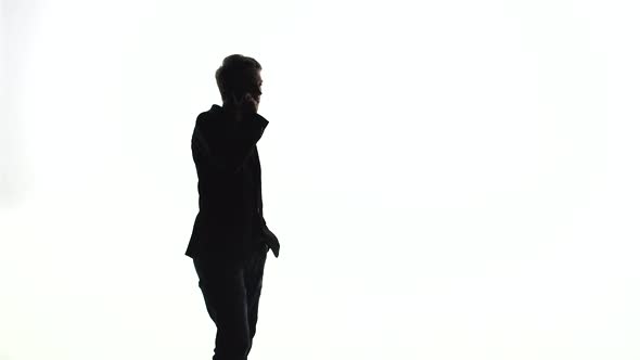 Silhouette of a Man in a Business Suit Walks and Speaks on the Phone