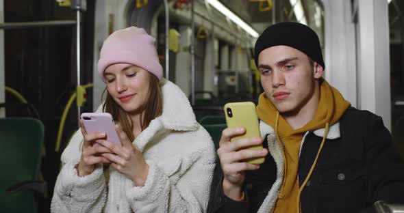 Young Couple Using Their Smartphones While Sitting on Seats in Public Transport. Good Looking Guy