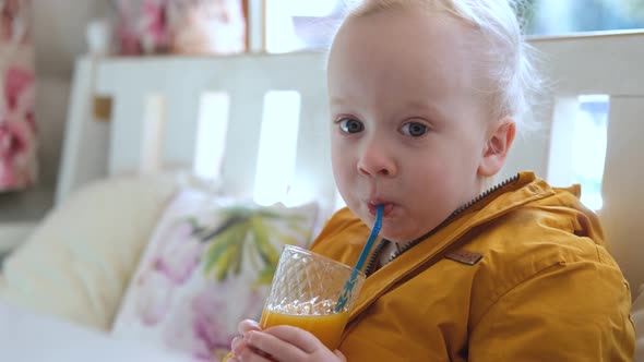 little boy drinks juice through a straw