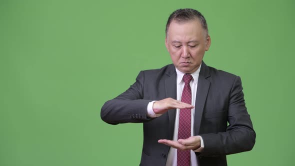 Mature Japanese Businessman Snapping Fingers and Showing Something