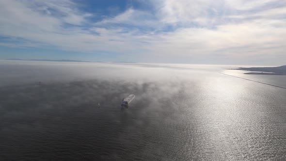 An early morning foggy aerial view of large cargo ships docked near Long Beach, California. Helicopt