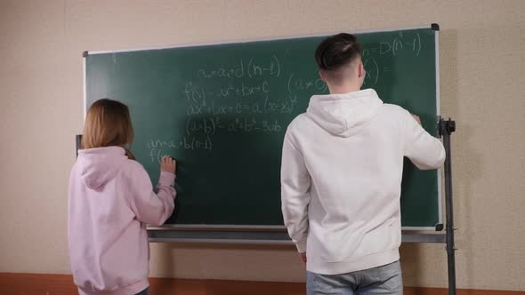 Two Teenagers Stand Near the Blackboard and Solve a Mathematical Problem