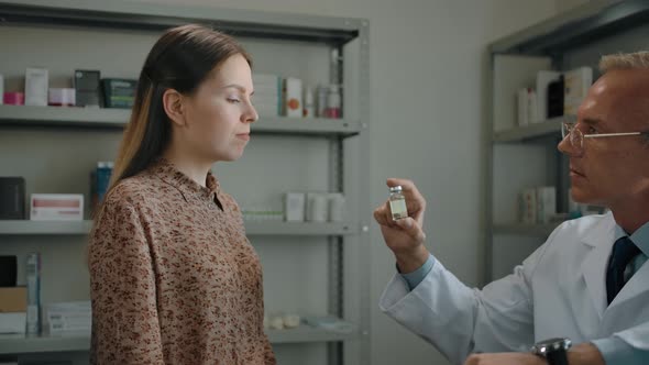 Closeup of Pharmacist Offering a COVID19 Vaccine to Female Client at Pharmacy