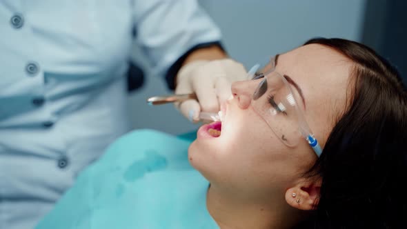 Dentist working with patient. Female dentist in uniform and gloves using dental instruments