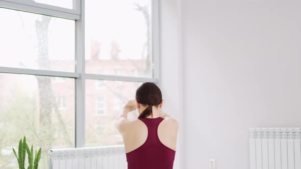 a Beautiful and Athletic Girl in a Burgundy Tracksuit Does Gymnastics in the Fitness Room