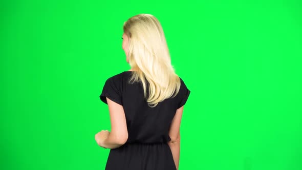 Blonde Girl Is Walking and Waving a Hand Welcoming. Chroma Key. Slow Motion. Back View.